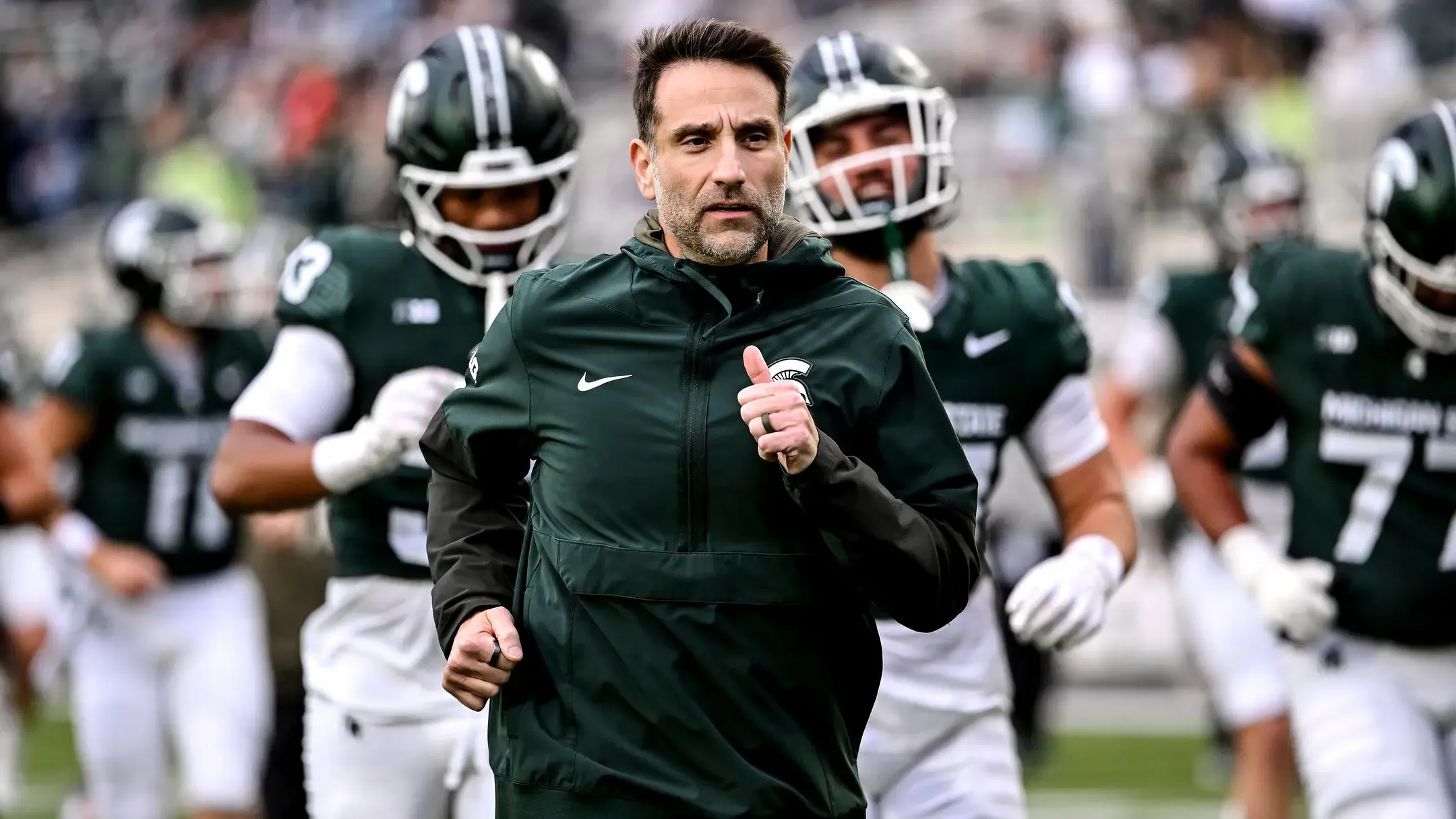 Joe Rossi jogging on the field in front of Michigan State players